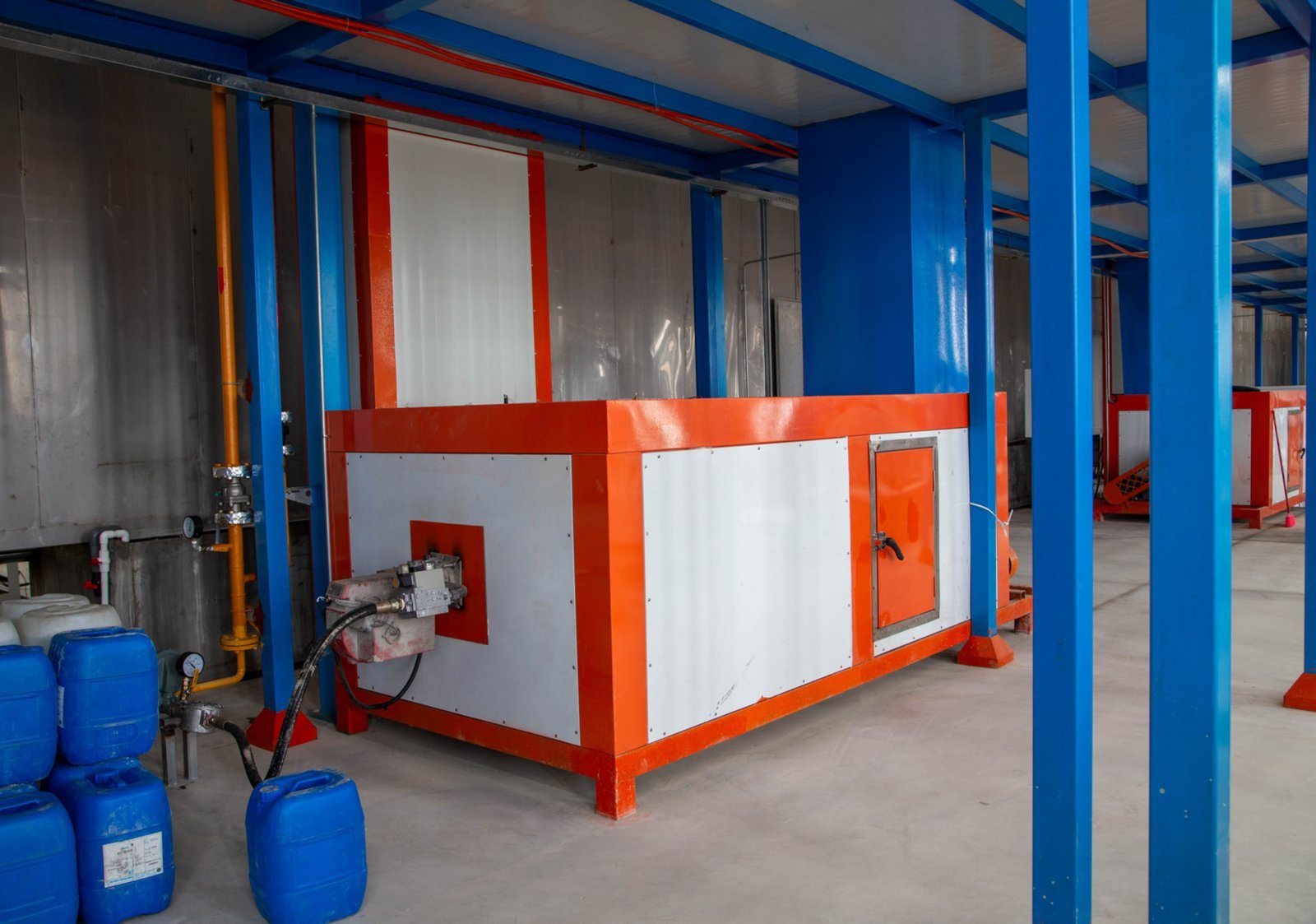 Powder coated workpieces entering gas curing oven on conveyor